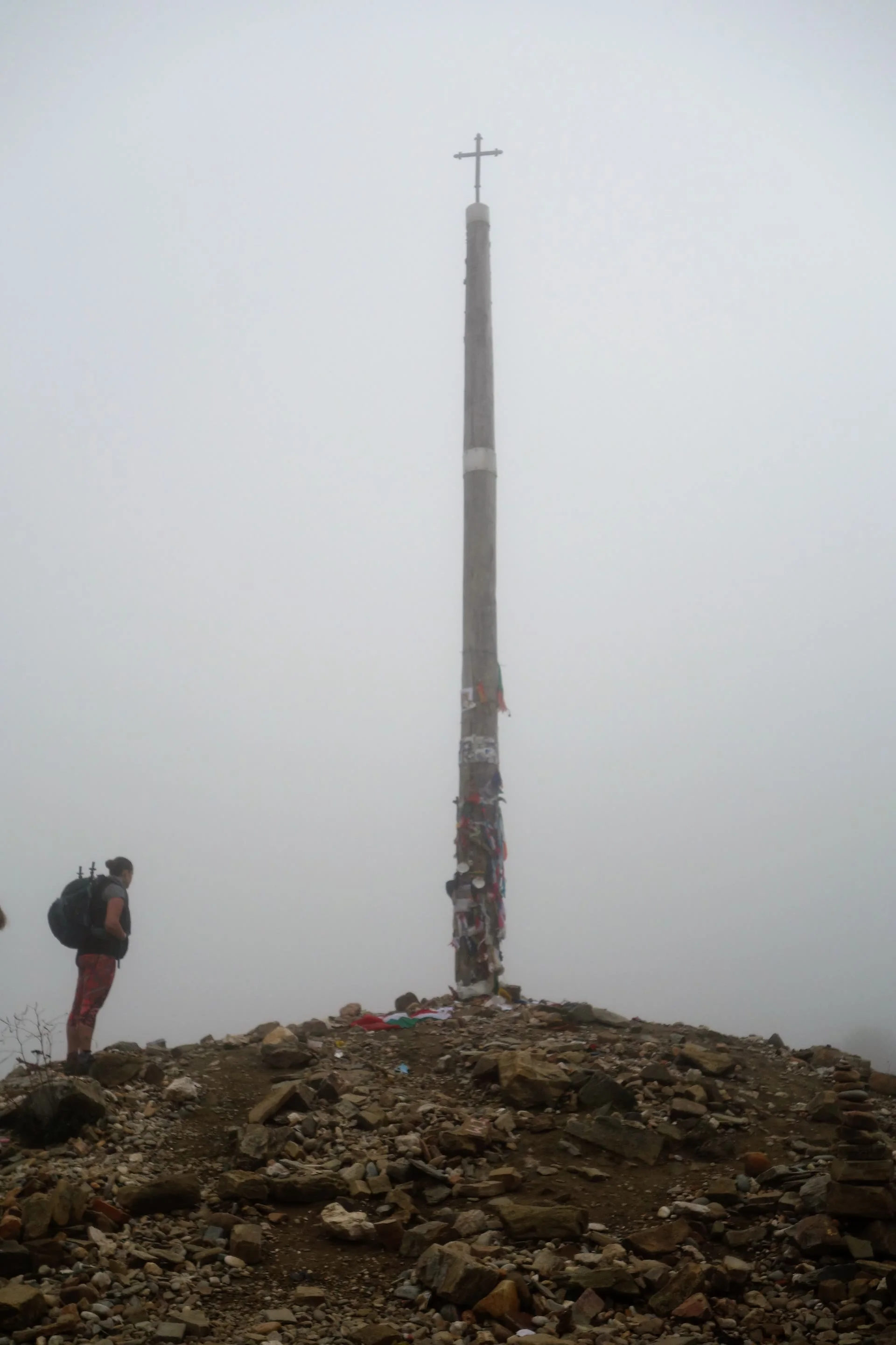 Wegkreuz im Nebel, dahinter verschwindet der Weg