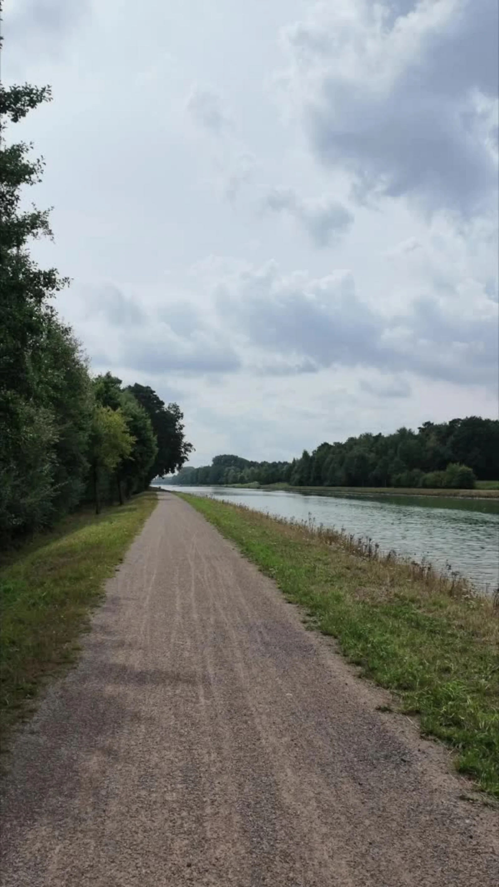 Kiesweg an einem Kanal, der geradeaus zum Horizont führt